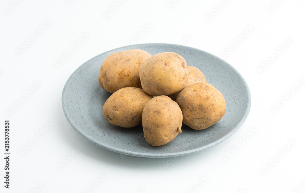 Fototapeta premium Fresh raw baby potatoes served on a grey ceramic plate isolated on white background