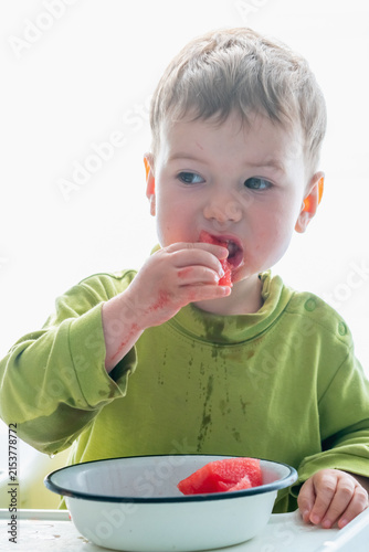 Candid unposed moment of a messy little boy naturally enjoying fresh watermelon at home.