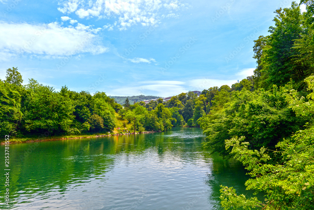 Obraz premium Baden im Kanton Aargau: Ruhiger Abschnitt der Limmat mit Schwimmern im türkisfarbenen Wasser vor idyllischer Hangbebauung