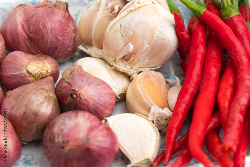 Fotografie Fresh red chilies shallots and garlic on ceramic plate isolated on white backgro