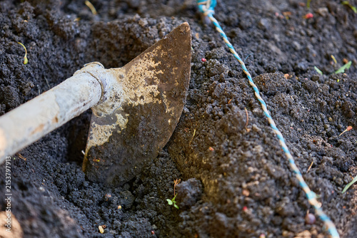 Konstfotografi Shovel digging into rich, fertile soil in garden close-up