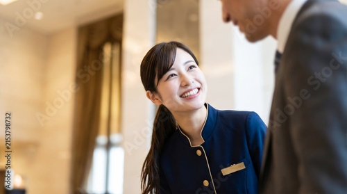 Fototapeta kuchenna ホテルの受付で笑顔で接客する女性スタッフと宿泊客の男性