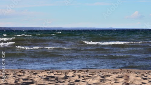 Calm waves along Vättern shoreline with distant land at sunset