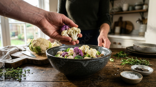 Fresh Cauliflower Florets Being Added To A Rustic Bowl