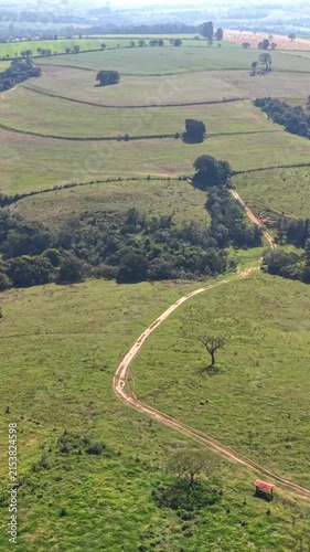 High angle aerial view of vast agricultural fields, pasture, and crop land captured by drone during a clear sunny day.