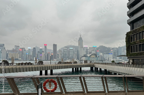 serene urban skyline from waterfront promenade with concrete, metal, and glass skyscrapers and bridge in gray and blue tones, static cityscape photography views.