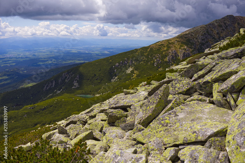 Foto Epic alpine landscape with lichen-covered rocks in foreground, a tarn, and deep valley in the High Tatra Mountains
