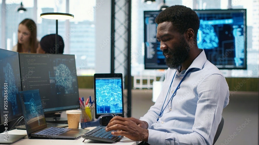 Fototapeta premium System administrator wears headphones and develops software with AI, debugging applications on a computer while listening to music during application testing.