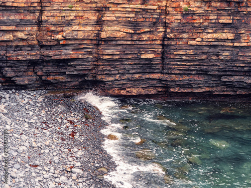 Photography Layered cliff face meets rocky shore