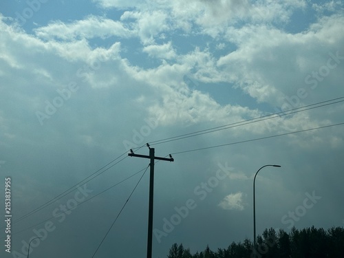 Power Cables and Electrical Power Lines Running Along a Rural Landscape With Utility Infrastructure and Open Sky