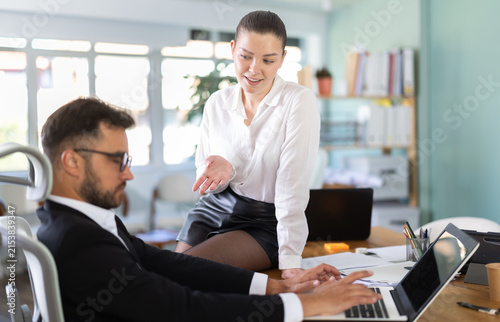 Portrait of adult business couple flirting at table at workplace in office