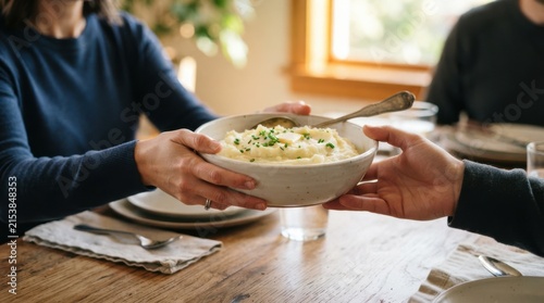 Family sharing a large bowl of creamy mashed potatoes at a dining table during a cozy homemade dinner party