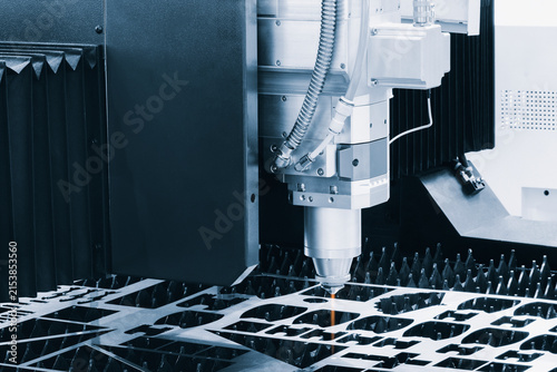 Obraz na płótnie Industrial laser cutter hovers above metal plate with precise holes