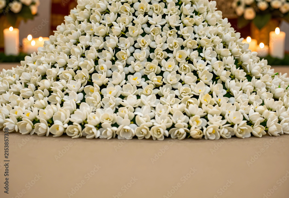 Fototapeta premium Abundant white jasmine flower arrangement with candles in the background, wedding and celebration decor, Abundant white jasmine flowers are arranged in a decorative display