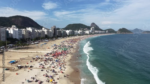 Rio de Janeiro, Brazil, aerial view of Copacabana Beach showing colourful umbrellas and people bathing in the ocean on a summer day. Tropical travel and vacation concept.