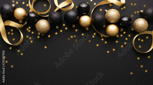 Elegant Christmas background with black and gold baubles and festive ribbons