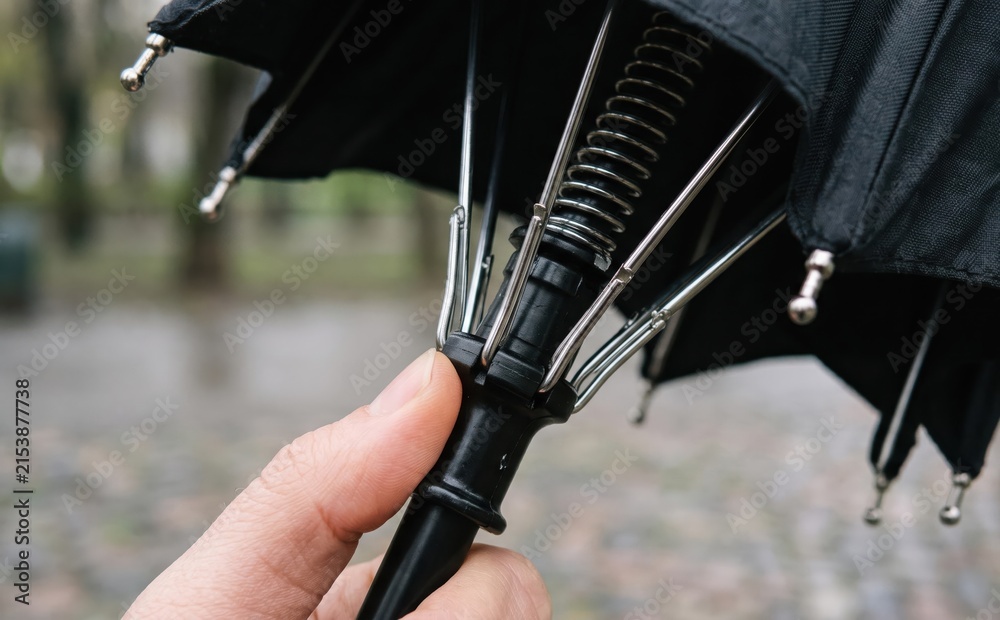 Fototapeta premium Close-up of an automatic folding umbrella mechanism with spring and metal ribs being held by a hand