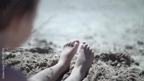 Young feet resting in grainy beach sand under bright sunlight. Ideal for holiday relaxation, outdoor play, seaside getaway and happy childhood lifestyle concepts.