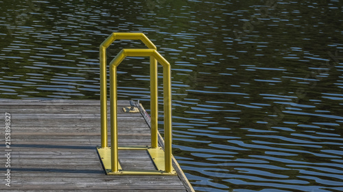Wooden dock featuring bright yellow safety ladder with dark water reflecting vibrant colors