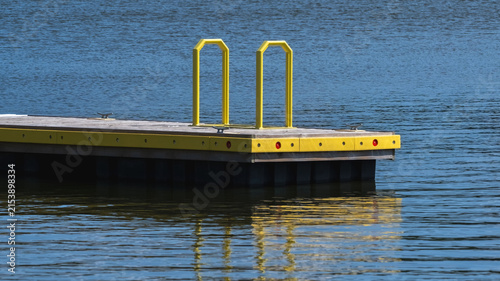 Wooden dock featuring bright yellow safety ladder with dark water reflecting vibrant colors