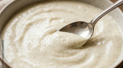 Bild auf Leinwand Close-up of creamy vanilla sauce with flecks, served in a rustic bowl with a silver spoon