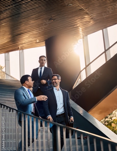 Three Professional Businessmen Walking Down Modern Staircase in Corporate Building