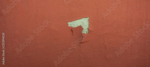 Peeling red wall paint revealing the base layer.