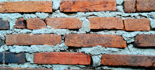 Rustic red brick wall with a thick cement mortar texture.