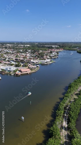 Single boat on Sykes Creek with waterfront homes on canals on one side and the Ulumay Wildlife Sanctuary on the other in Merritt Island, Florida.