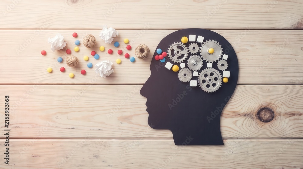 Naklejka premium Human Head Silhouette with Metal Gears and Colorful Objects on Wood Background for Psychology and Creative Thinking Content