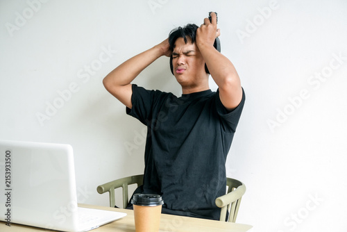 Quadro su tela Stressed Male Student Wearing Headphones Gripping Hair in Despair at Desk Comput
