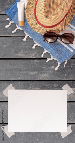 Summer Wallpaper with Straw Hat, Towel, Sunglasses, Protection Cream and White Blank Free Space Paper Sheet with Adhesive Tape on Wooden Surface. File with Clipping Path.