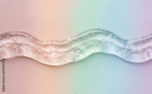 Transparent cosmetic gel smear with bubbles on a pastel rainbow background representing skincare beauty and serum texture