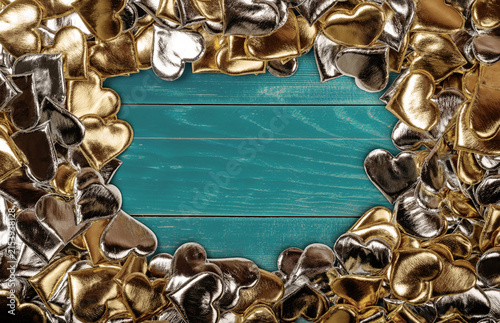 Golden and Silver Heart Shapes on Teal Wooden Background for Romantic Themes