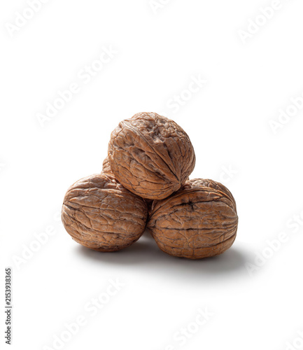 Unshelled textured walnuts in a small pile on a white backdrop