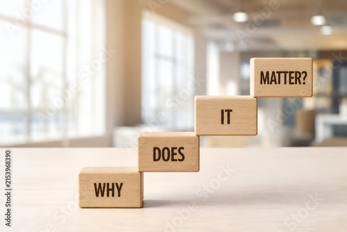 The Significance of 'Why': Wooden blocks spelling out WHY IT DOES MATTER? arranged in ascending steps, symbolizing purpose and motivation in a well-lit, modern office setting.