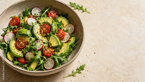 Vibrant Avocado Salad: A delicious and healthy salad featuring fresh avocado, cherry tomatoes, sliced radishes, and leafy greens, presented in a rustic bowl on a textured surface.