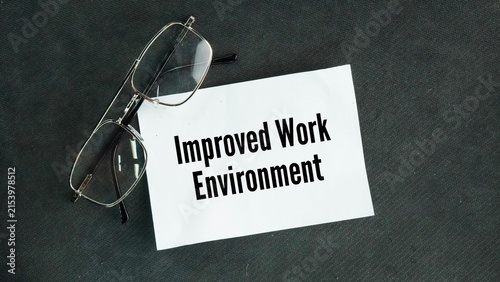 Glasses and paper with the words Improved work environment. a safer, more supportive, and better-organized workplace that boosts employee happiness, health, and productivity.