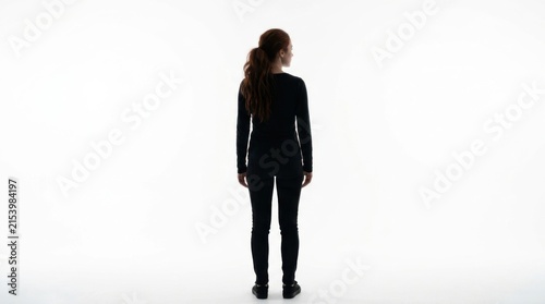 Young woman with long red hair standing and looking away in dark clothes