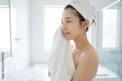白いタオルで顔を拭く若い女性（スキンケア・保湿・美容・洗顔）