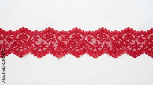 Horizontal red lace trim ribbon featuring intricate floral embroidery and decorative scalloped edges laid flat on a plain white surface for sewing and craft projects.