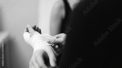 Nurse checking a patient's wristband and pulse with gloved hands, representing hospital care, medical examination and healthcare professional service.