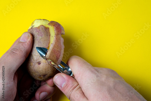 Hands peeling a potato with a vegetable peeler