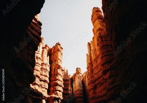Dramatic slot canyon view of towering orange hoodoos against a bright sky, natural landscape