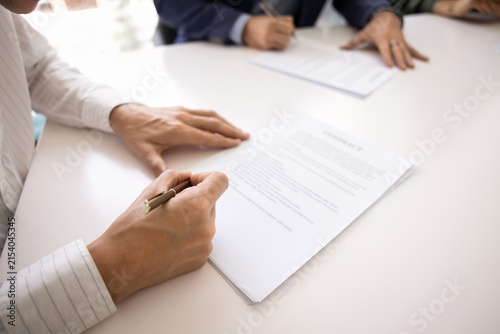Cropped close up hands of male business representatives or managers validating contract with written signatures confirming enterprise deal authorizing service documents after professional discussion