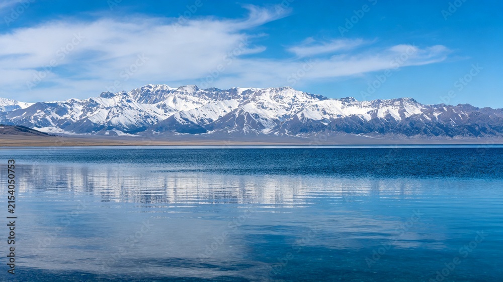Fototapeta premium Snow Capped Mountain Range Reflected in Calm Blue Lake Under Clear Sky