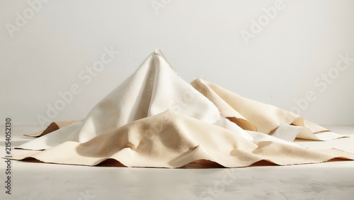 Abstract composition of draped white and beige fabric sheets arranged in soft, flowing mountain-like peaks on a neutral surface background