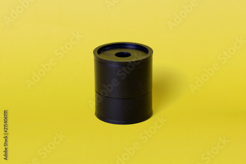 Black cylindrical plastic container with a round opening