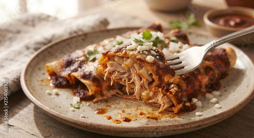  A focus-stacked, mouth-watering image capturing a fork lifting a piece of a cheesy chicken enchilada, showing the tender shredded meat inside the softened corn tortilla covered in rich chili sauce.