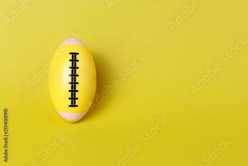 Yellow American football toy on a bright yellow background